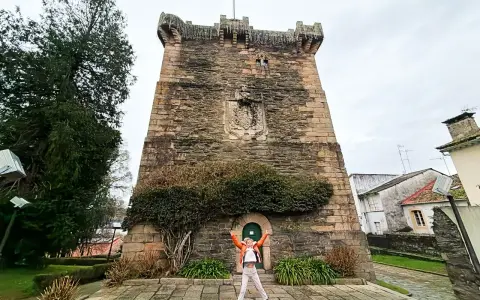 Persona salta de alegría frente a la Torre de los Andrade, un lugar imprescindible que ver en Pontedeume.