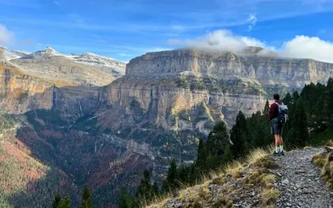 Senderista admira el imponente paisaje de los Pirineos. Las **rutas Pirineos** ofrecen vistas espectaculares de cañones y cascadas.