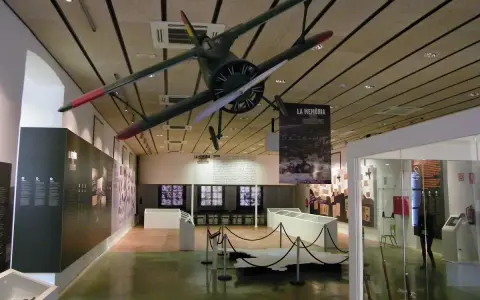 Interior del museo de la Batalla del Ebro, con un avión colgado del techo y expositores.