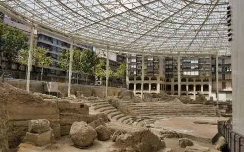 Antiguas ruinas romanas en Zaragoza, protegidas bajo una moderna estructura de cristal y metal.