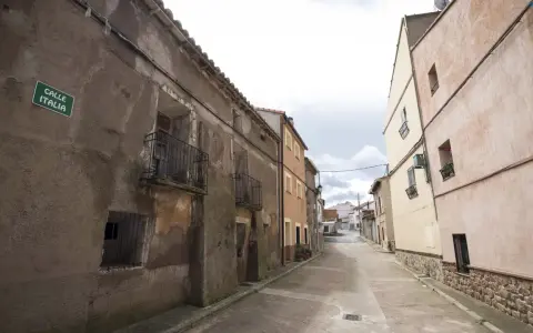 Calle Italia en Villar del Salz, un pueblo con casas antiguas y un cielo nublado.