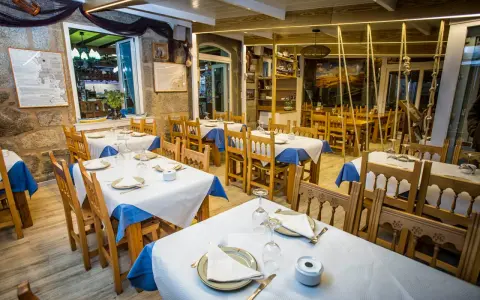 Mesas puestas y listas para comer en Muxía. Ambiente acogedor con decoración marinera, perfecto para disfrutar de la gastronomía local.