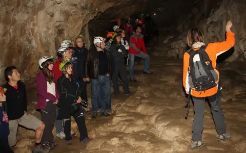 Grupo de exploradores con cascos y linternas en la cueva del oso, observando formaciones rocosas.