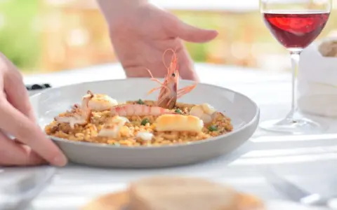 Un plato de paella de marisco servido con vino tinto, ideal para saber donde comer en Menorca.