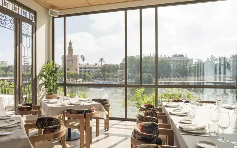 Mesas elegantemente puestas con vistas a la Torre del Oro. Un lugar ideal para disfrutar de una experiencia culinaria en el mejor restaurante Sevilla.