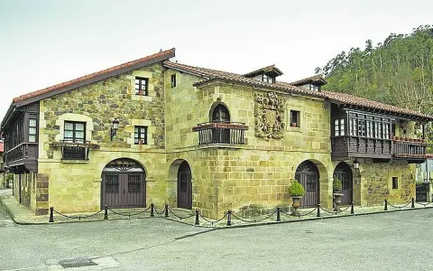 Edificio histórico de piedra con balcones de madera, ideal para saber donde comer en Lierganes.