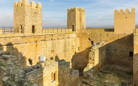El castillo de Sádaba, con sus imponentes torres de piedra dorada, se alza bajo un cielo azul, invitando a imaginar batallas y leyendas.