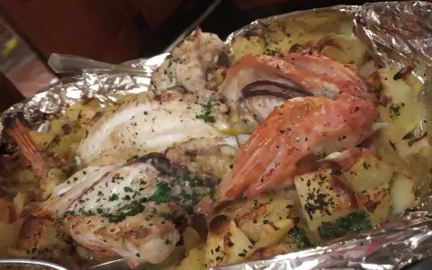 Delicioso pescado y gambas al horno con patatas, un plato típico de la casa Juanita Begur.