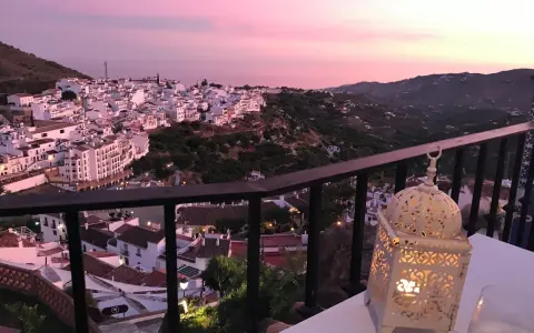Atardecer rosado sobre Frigiliana. Una linterna ilumina la mesa, perfecta para decidir dónde comer en Frigiliana.