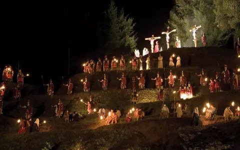 Representación nocturna del vía crucis en Sant Hilari, con antorchas iluminando a soldados romanos y figuras bíblicas en una ladera.