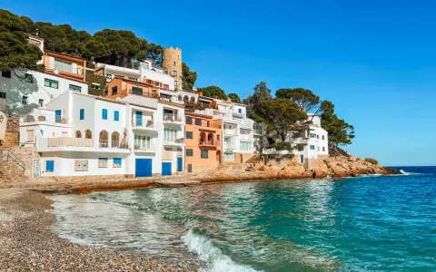 Pueblo blanco en la costa, ideal para tu guía Costa Brava. Casas blancas y naranjas con vistas al mar turquesa.