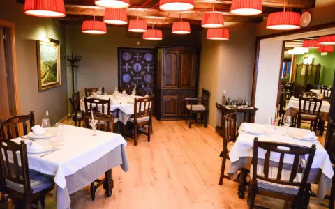 Mesas puestas y listas para comer en Morella. El restaurante tiene lámparas rojas, muebles de madera oscura y un cuadro en la pared.