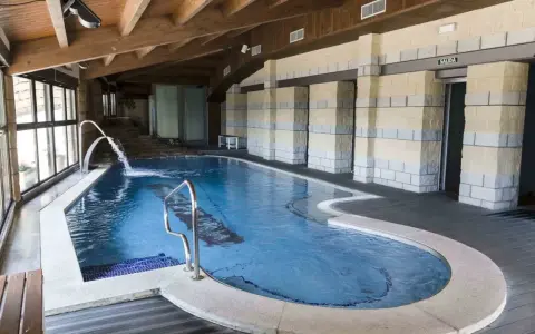 Piscina interior con cascadas y escaleras de piedra, ideal para relajarse en las **Vilas del Turbon**.