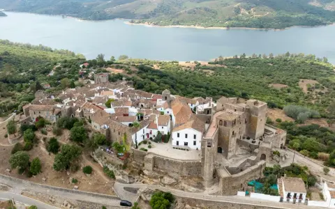 Vista aérea de Castellar de la Frontera, un pueblo blanco con un castillo, rodeado de vegetación y un embalse. Un lugar que evoca la paz de los hippies.