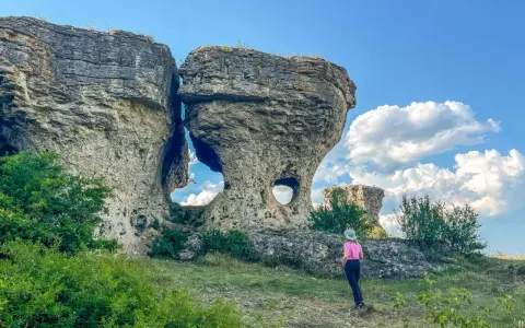 Una persona observa formaciones rocosas únicas, como si fueran las tuerces ruta circular, bajo un cielo azul con nubes.