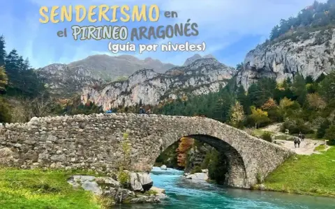 Puente de piedra sobre río turquesa en la montaña de Pirineos. Senderismo en el Pirineo Aragonés.