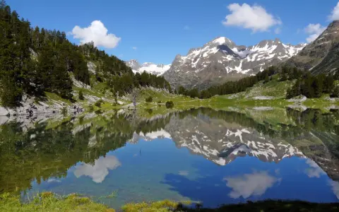 Espectacular reflejo de montañas nevadas y bosques en un lago sereno. Un lugar ideal que ver en el Pirineo Aragonés para conectar con la naturaleza.