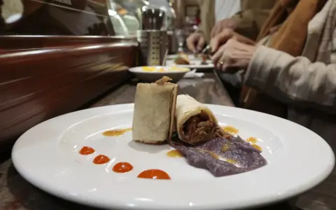 Dos rollitos de carne deshebrada con puré morado y salsa, un delicioso bocado para comer en Plasencia.