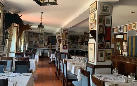 Mesas puestas para comer en ronda, decorado con cabezas de toro y carteles taurinos.