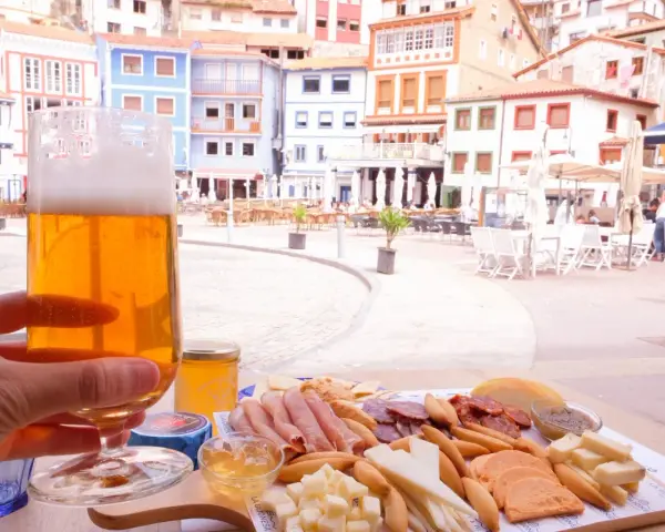 Disfrutando de una cerveza y una tabla de quesos y embutidos en Cudillero, con las coloridas casas de fondo.