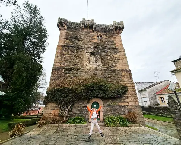 Persona salta de alegría frente a la Torre de los Andrade, un lugar imprescindible que ver en Pontedeume.