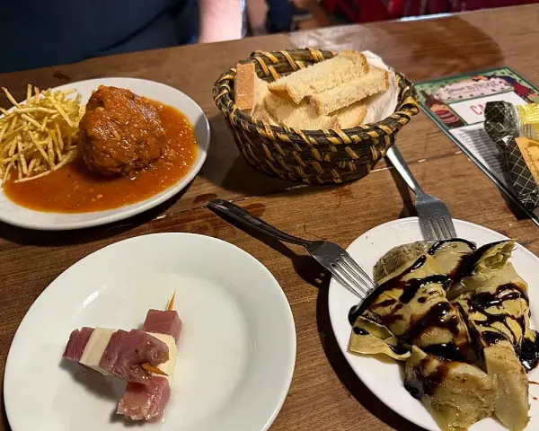 Deliciosos platos para comer en Jerez de la Frontera: albóndiga con patatas, pinchos de jamón y queso, y alcachofas con reducción de balsámico.