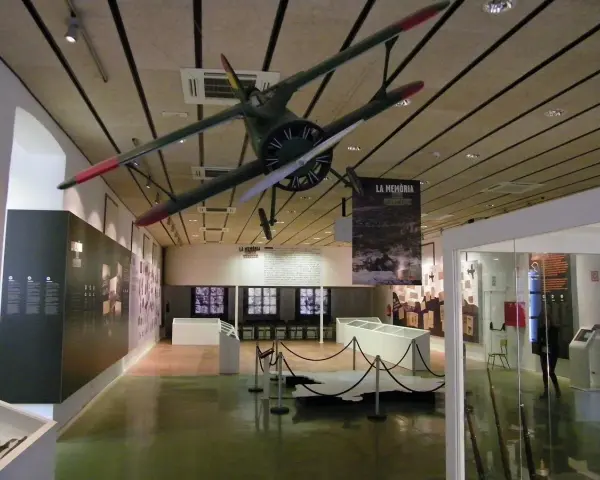 Interior del museo de la Batalla del Ebro, con un avión colgado del techo y expositores.