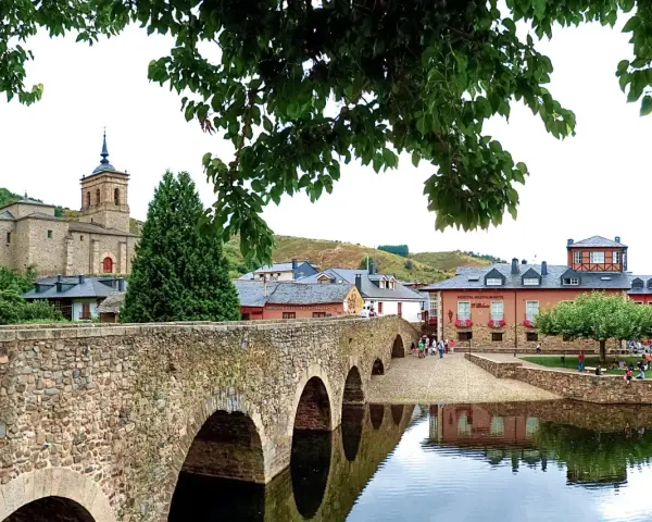 Puente romano y el pueblo de Molina Seca que ver. Iglesia antigua, casas y río con reflejos.