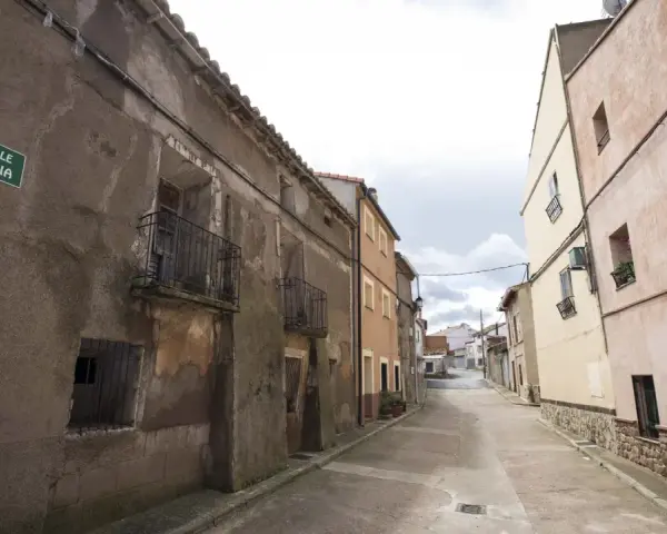 Calle Italia en Villar del Salz, un pueblo con casas antiguas y un cielo nublado.