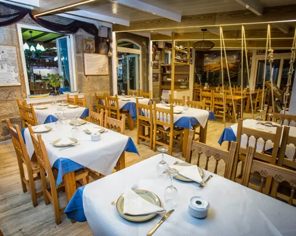 Mesas puestas y listas para comer en Muxía. Ambiente acogedor con decoración marinera, perfecto para disfrutar de la gastronomía local.
