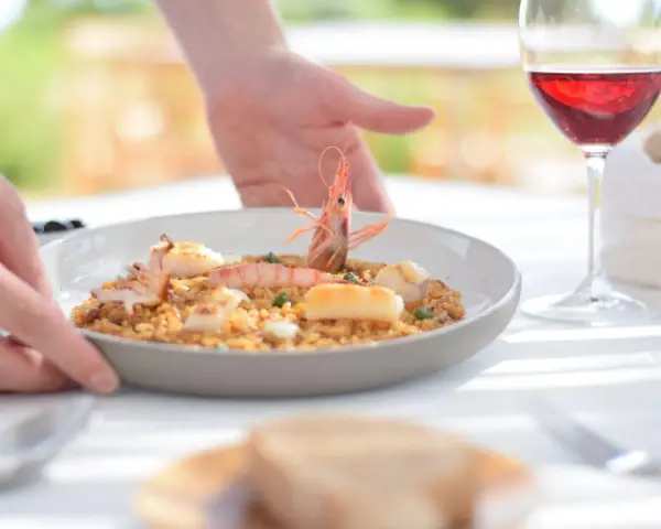 Un plato de paella de marisco servido con vino tinto, ideal para saber donde comer en Menorca.