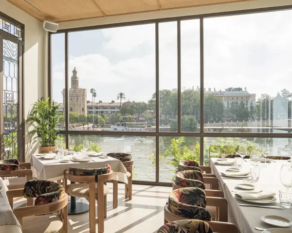 Mesas elegantemente puestas con vistas a la Torre del Oro. Un lugar ideal para disfrutar de una experiencia culinaria en el mejor restaurante Sevilla.