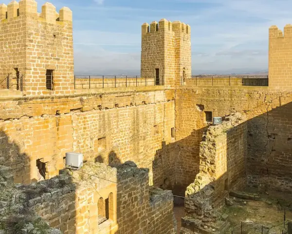 El castillo de Sádaba, con sus imponentes torres de piedra dorada, se alza bajo un cielo azul, invitando a imaginar batallas y leyendas.