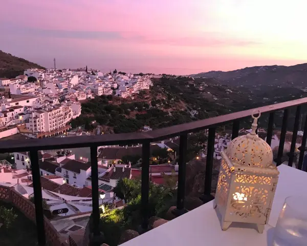 Atardecer rosado sobre Frigiliana. Una linterna ilumina la mesa, perfecta para decidir dónde comer en Frigiliana.
