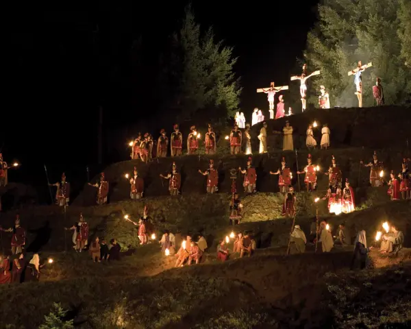 Representación nocturna del vía crucis en Sant Hilari, con antorchas iluminando a soldados romanos y figuras bíblicas en una ladera.