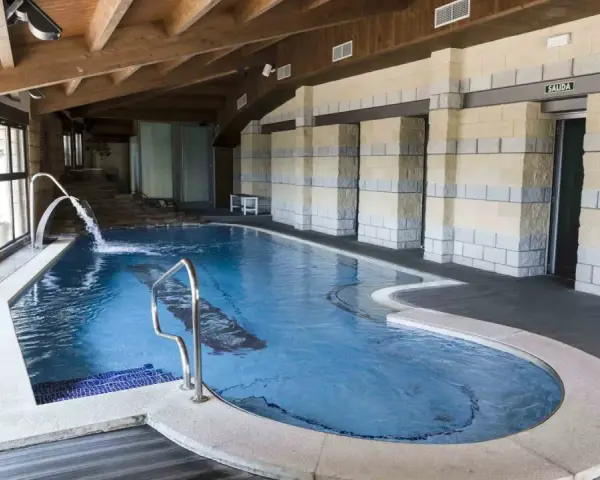 Piscina interior con cascadas y escaleras de piedra, ideal para relajarse en las **Vilas del Turbon**.