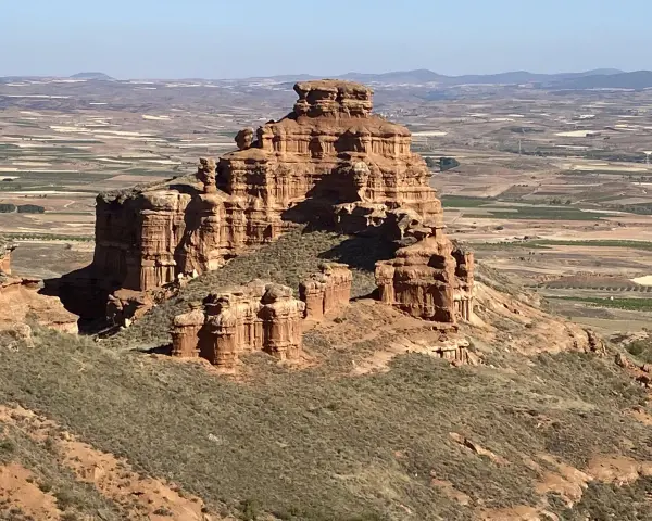 Impresionante formación rocosa en Villarroya de la Sierra, con un paisaje de campos cultivados al fondo.