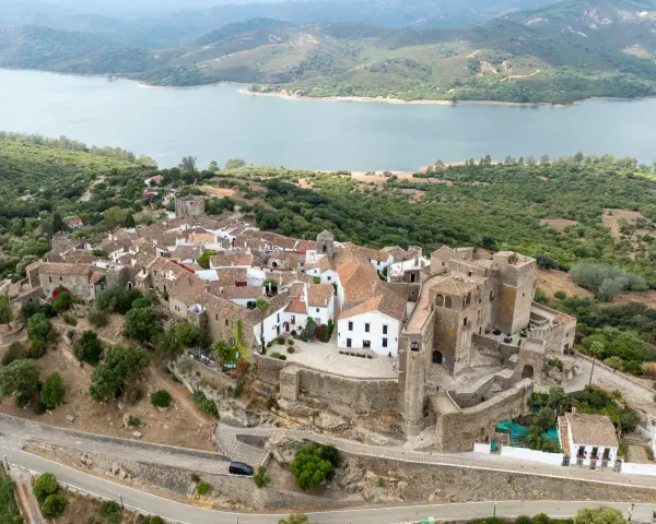 Vista aérea de Castellar de la Frontera, un pueblo blanco con un castillo, rodeado de vegetación y un embalse. Un lugar que evoca la paz de los hippies.