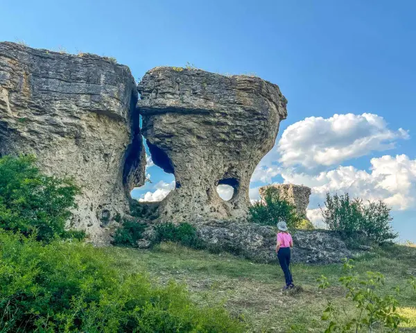 Una persona observa formaciones rocosas únicas, como si fueran las tuerces ruta circular, bajo un cielo azul con nubes.