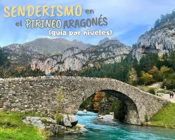 Puente de piedra sobre río turquesa en la montaña de Pirineos. Senderismo en el Pirineo Aragonés.