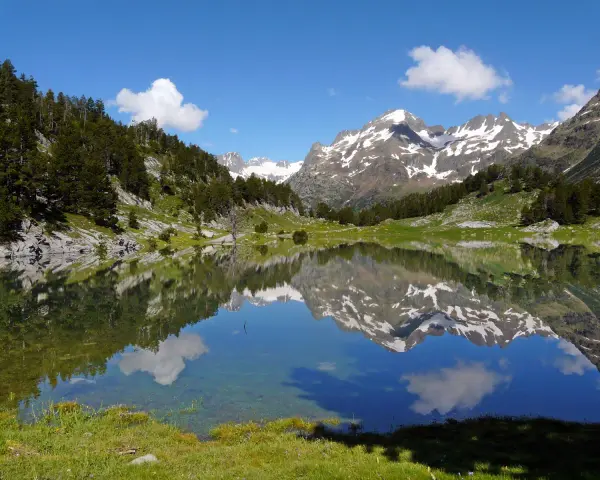 Espectacular reflejo de montañas nevadas y bosques en un lago sereno. Un lugar ideal que ver en el Pirineo Aragonés para conectar con la naturaleza.