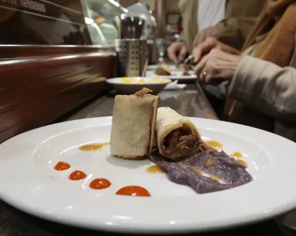 Dos rollitos de carne deshebrada con puré morado y salsa, un delicioso bocado para comer en Plasencia.