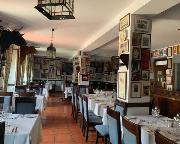Mesas puestas para comer en ronda, decorado con cabezas de toro y carteles taurinos.