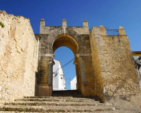 Antigua puerta de Medina Sidonia, con escalinata de piedra y cielo azul. Merece la pena visitar Medina Sidonia.