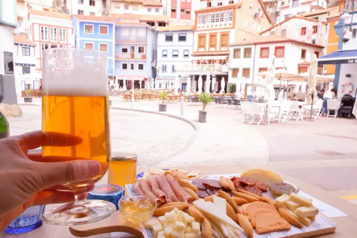 Disfrutando de una cerveza y una tabla de quesos y embutidos en Cudillero, con las coloridas casas de fondo.