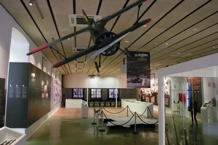 Interior del museo de la Batalla del Ebro, con un avión colgado del techo y expositores.