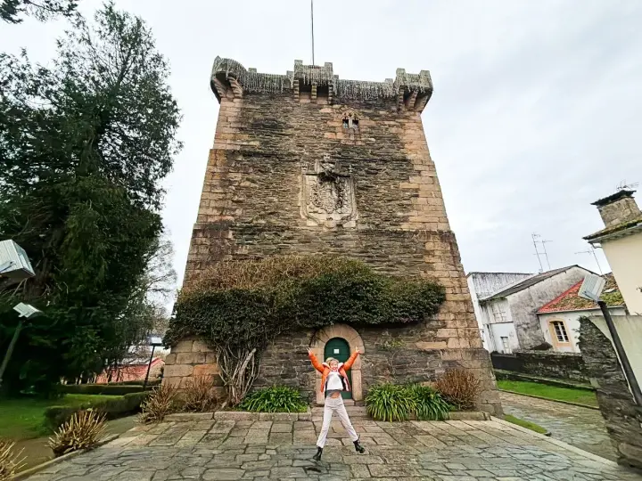 Persona salta de alegría frente a la Torre de los Andrade, un lugar imprescindible que ver en Pontedeume.