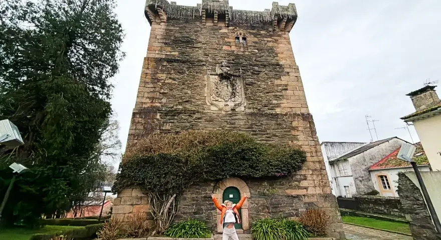 Persona salta de alegría frente a la Torre de los Andrade, un lugar imprescindible que ver en Pontedeume.