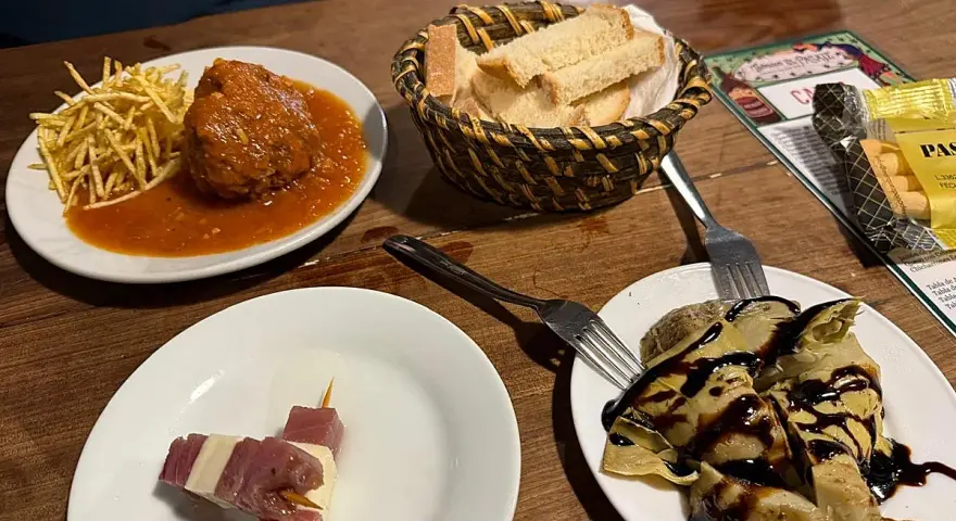 Deliciosos platos para comer en Jerez de la Frontera: albóndiga con patatas, pinchos de jamón y queso, y alcachofas con reducción de balsámico.