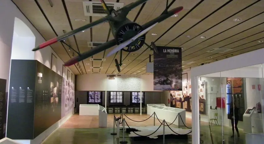 Interior del museo de la Batalla del Ebro, con un avión colgado del techo y expositores.